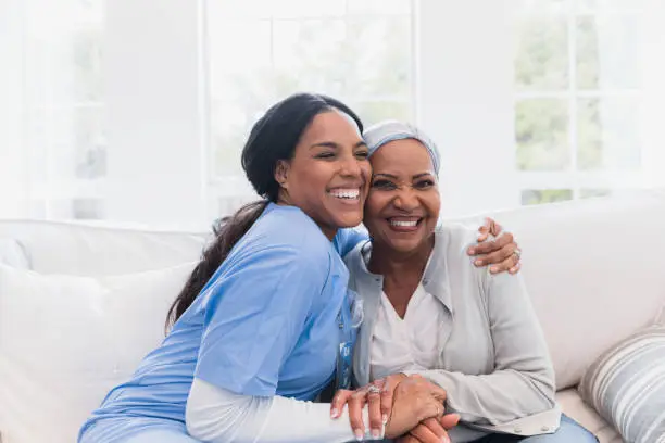The elderly woman enjoys an embrace from her favorite home healthcare nurse. .